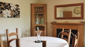 A dining room with a round table, chairs, a cabinet with glass doors, a fireplace, and a wall clock. - 3 bedroom accommodation in Burnsall (Burnsall)