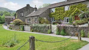 A stone building with a white picket fence, a paved walkway, and a grassy area. - 3 bedroom accommodation in Burnsall (Burnsall)