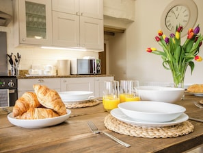 A breakfast setting with croissants, orange juice, and tulips on a wooden table.