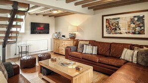A living room with a brown leather sofa, wooden coffee table, and a TV mounted on the wall. - 7 bedroom accommodation in Bradbourne, near Ashbourne (Bradbourne, near Ashbourne)