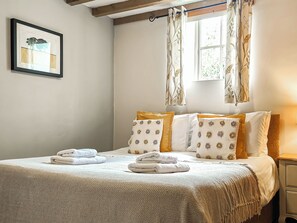 A neatly made bed with a white and beige bedspread, two pillows with floral patterns, and a window with curtains. - 7 bedroom accommodation in Bradbourne, near Ashbourne (Bradbourne, near Ashbourne)