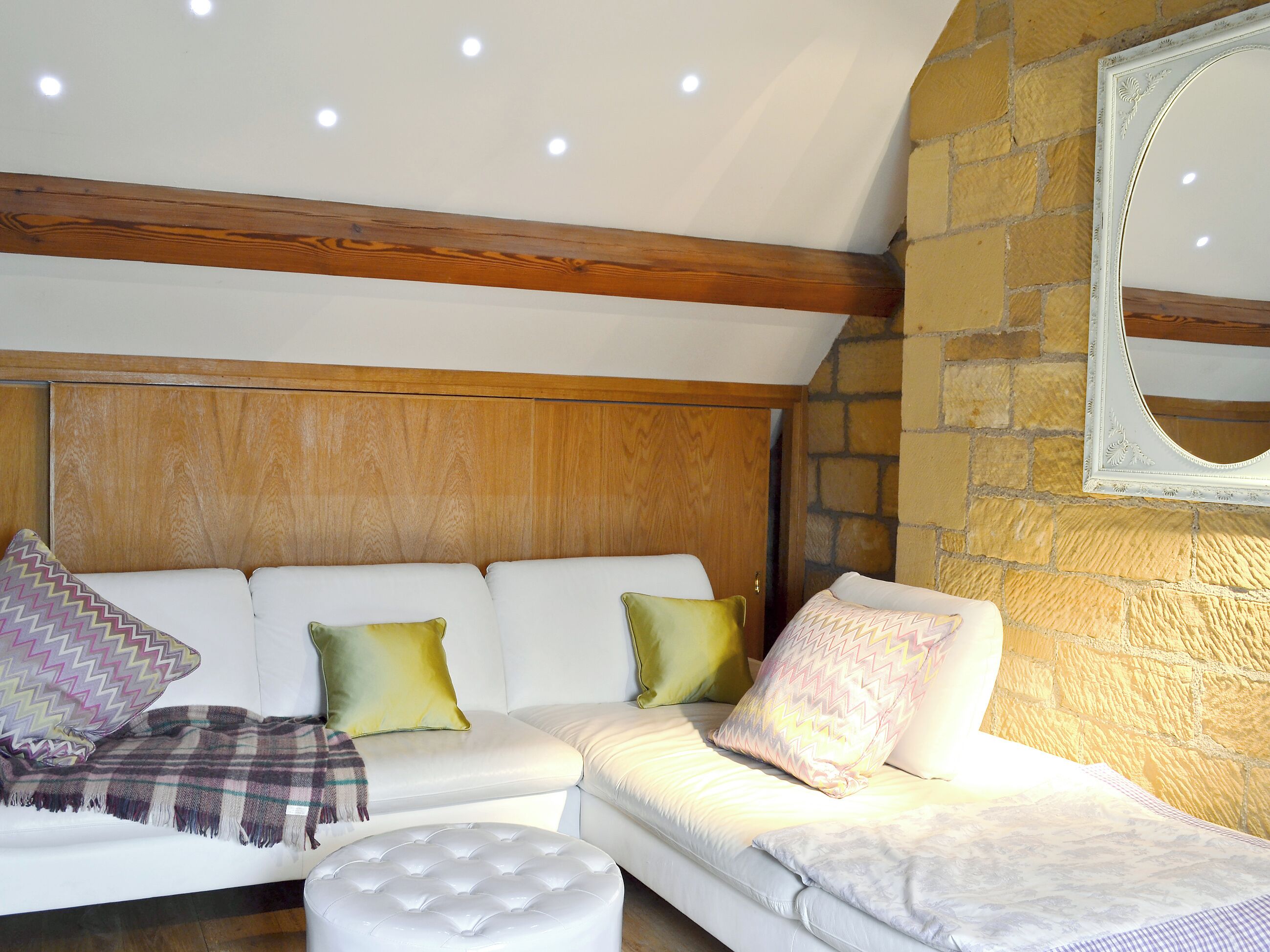 Una sala moderna con un sofá blanco, dos otomanas y almohadones decorativos.