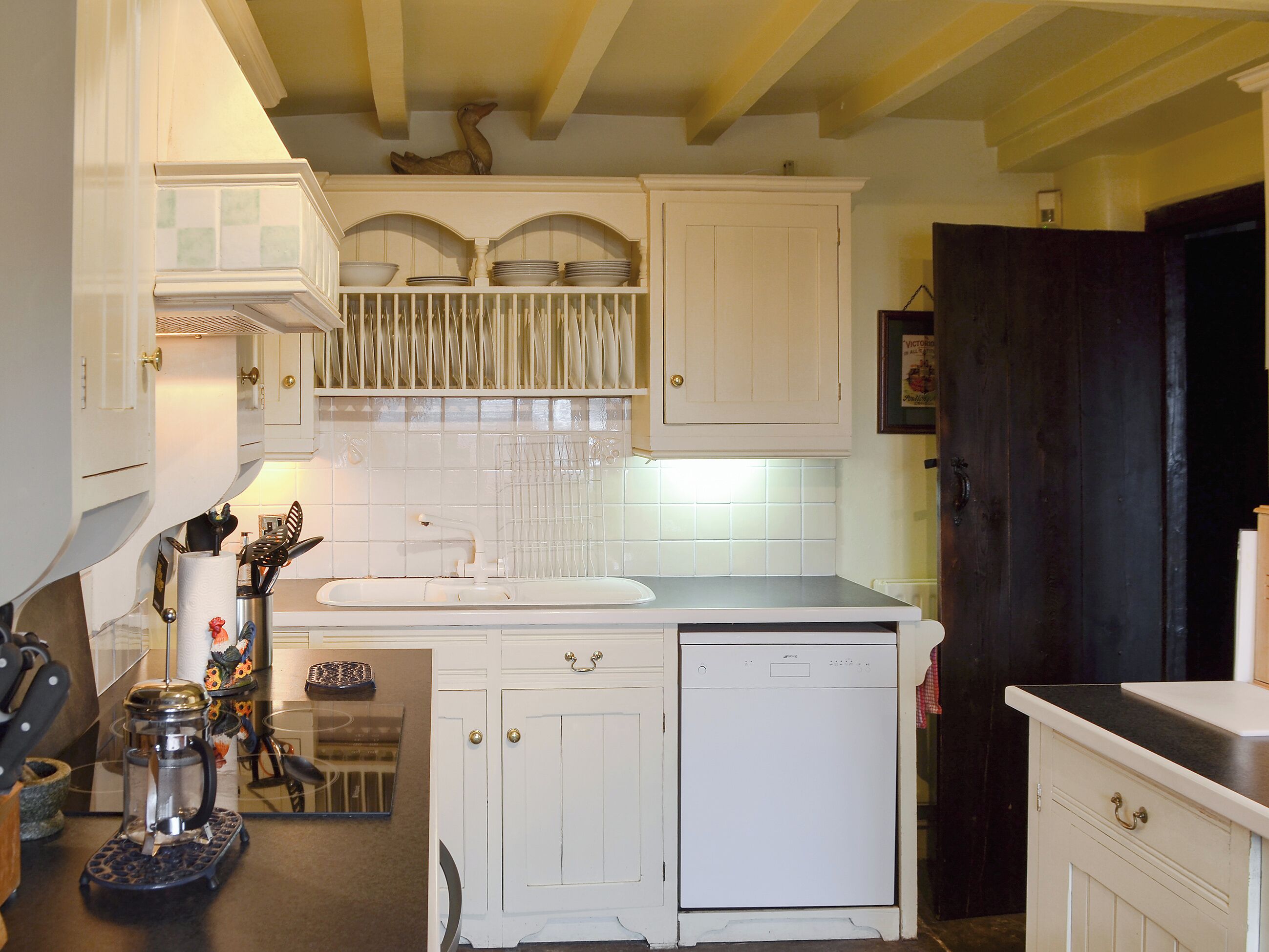 A kitchen with white cabinetry, a dishwasher, and a coffee maker.