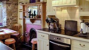 A kitchen with a stone wall, wooden cabinets, and a built-in oven. - 3 bedroom accommodation in Castleton (Castleton)