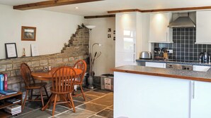 Une cuisine moderne avec un escalier en pierre, des meubles blancs et un coin repas avec des chaises en bois.