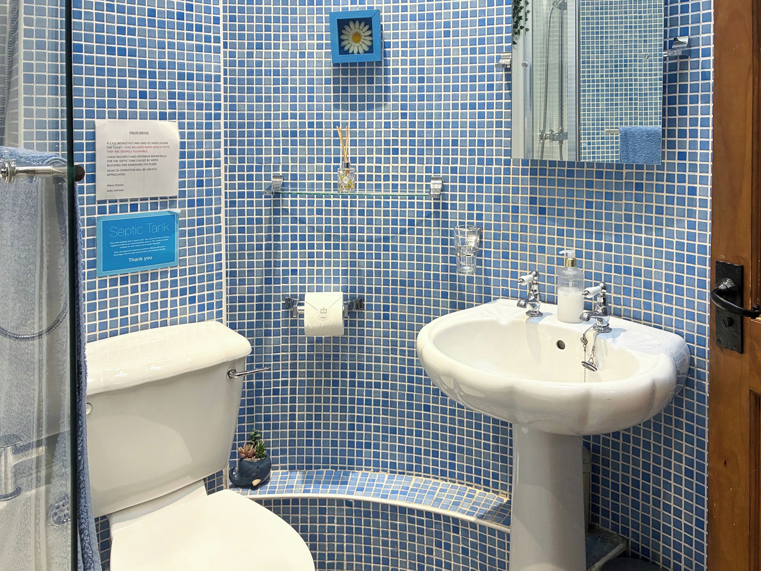 A bathroom with a toilet, sink, and blue-tiled walls.