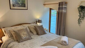 Ein ordentlich bezogenes Bett mit einer weißen und beige gestreiften Bettdecke, mehreren Kissen und einem aufgerollten weißen Handtuch.