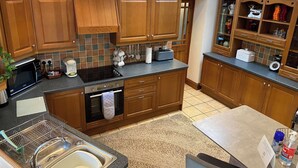 Eine Küche mit Holzausstattung, Backofen, Mikrowelle und Spüle.