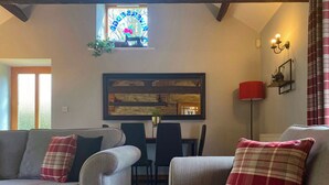 Ein gemütliches Wohnzimmer mit zwei grauen Sofas, jedes mit einem karierten Kissen, einem gerahmten Kunstwerk über einem Kamin und einem kleinen Tisch mit Stühlen.