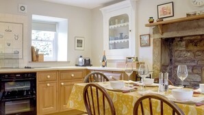 A kitchen with wooden cabinets, a dining table with chairs, a built-in oven, and a stone fireplace. - 3 bedroom accommodation in Kettlewell, near Grassington (Kettlewell, near Grassington)