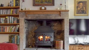A cozy living room with a stone fireplace, bookshelves, a television, and a painting on the wall. - 3 bedroom accommodation in Kettlewell, near Grassington (Kettlewell, near Grassington)
