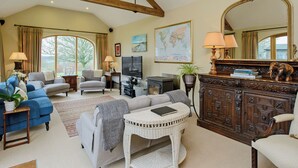A spacious living room with a high ceiling, large windows, a fireplace, and a world map on the wall. - The Stables at Weedon Hill Farm (Weedon, near Daventry)