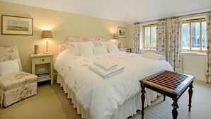A bedroom with a bed, a chair, a table, and a window with curtains. - The Stables at Weedon Hill Farm (Weedon, near Daventry)
