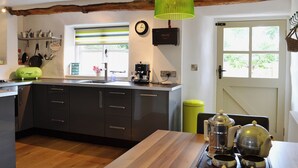 Una cocina moderna con una isla de madera, una cafetera y una lámpara colgante verde.