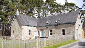 A stone building with a gravel driveway and a wooden fence. - 2 bedroom accommodation in Rosehall, near Lairg (Rosehall, near Lairg)