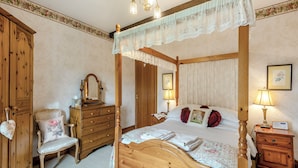 Un lit à baldaquin, des meubles en bois, une commode, une chaise et des lampes de chevet.