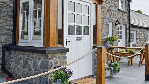 A stone building with a wooden door labeled 'CESO,' a rope barrier, and potted plants. - Golygfar Mynydd - Mountain View (Pontrhydfendigaid, near Tregaron)