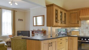 Una cocina con armarios de madera, horno empotrado y una zona de comedor con sofá y mesa.