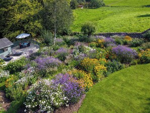 A house with a patio, surrounded by a garden with various flowers.