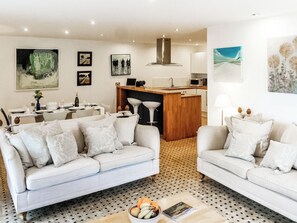 A modern living room with two sofas, a dining area, and a kitchen.