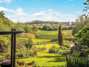 Ein Garten mit Rasenfläche, einer Holzpergola und vielfältigen Pflanzen.