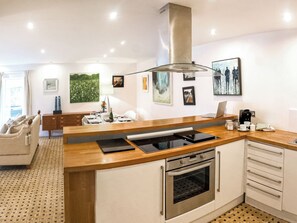 A modern kitchen with a central island, built-in oven, and stainless steel range hood.