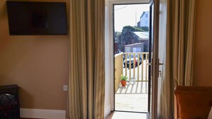 A room with a sliding glass door leading to a balcony with a view of a residential area.