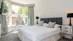 A neatly arranged bedroom with a large bed, two bedside tables with lamps, a dresser, and a mirror. - 3 bedroom accommodation in Filey (Filey)