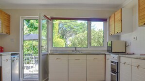 Una cocina compacta con ventana, armarios integrados, un lavamanos y una estufa.