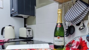 Une cuisine équipée d’une bouteille de champagne Taittinger, d’une bouilloire, d’un grille-pain et d’un livre de recettes.
