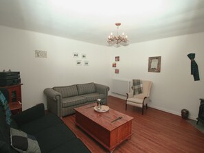 A living room with a sofa, armchair, wooden coffee table, and a chandelier. - 3 bedroom accommodation in Poolewe, near Gairloch (Poolewe, near Gairloch)