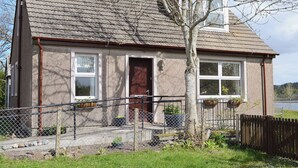 Una casa petita amb teulada inclinada, una porta d'entrada i una finestra.