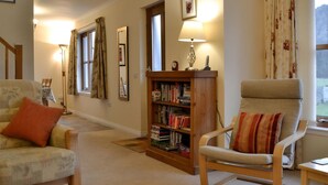 Un salon confortable avec un canapé, un fauteuil et une bibliothèque.