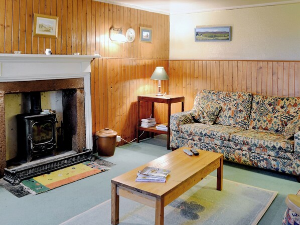 A cozy room with a fireplace, a sofa, a wooden table, and a lamp.