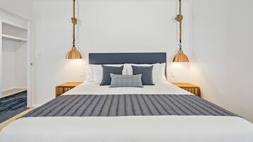 Un lit bien fait, avec une couvre-lit à rayures, deux tables de chevet et une tête de lit.