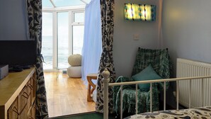 A room with a bed, a television, a window with curtains, a small table, and a chair. - 2 bedroom accommodation in Buckie, near Cullen (Buckie, near Cullen)