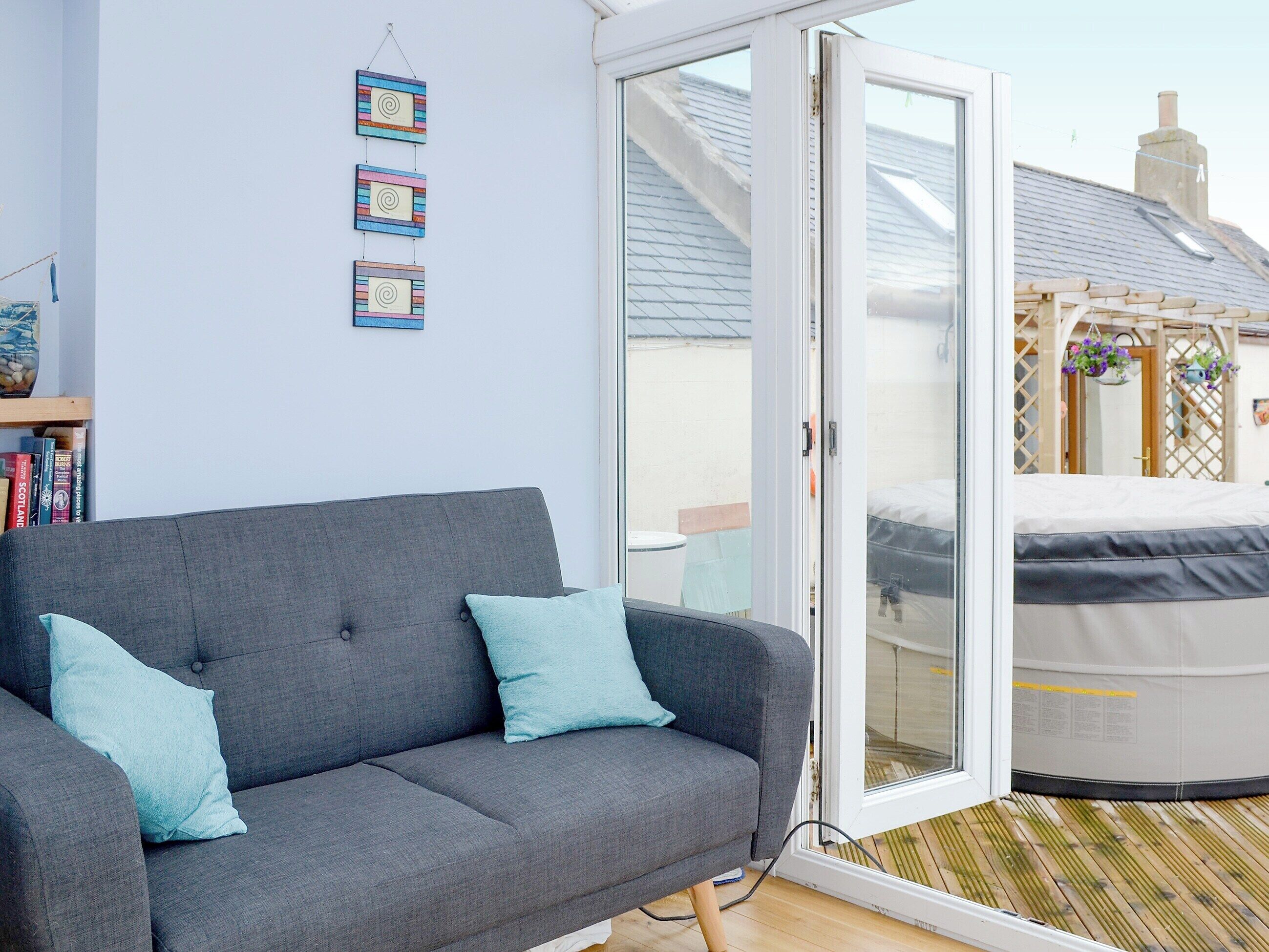 A grey sofa with two light blue cushions, a white sliding glass door, and a wooden floor.