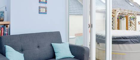 A grey sofa with two light blue cushions, a white sliding glass door, and a wooden floor.