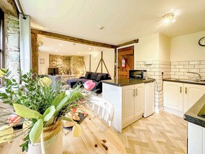 A kitchen with white cabinets, a microwave, and a wooden herringbone floor.