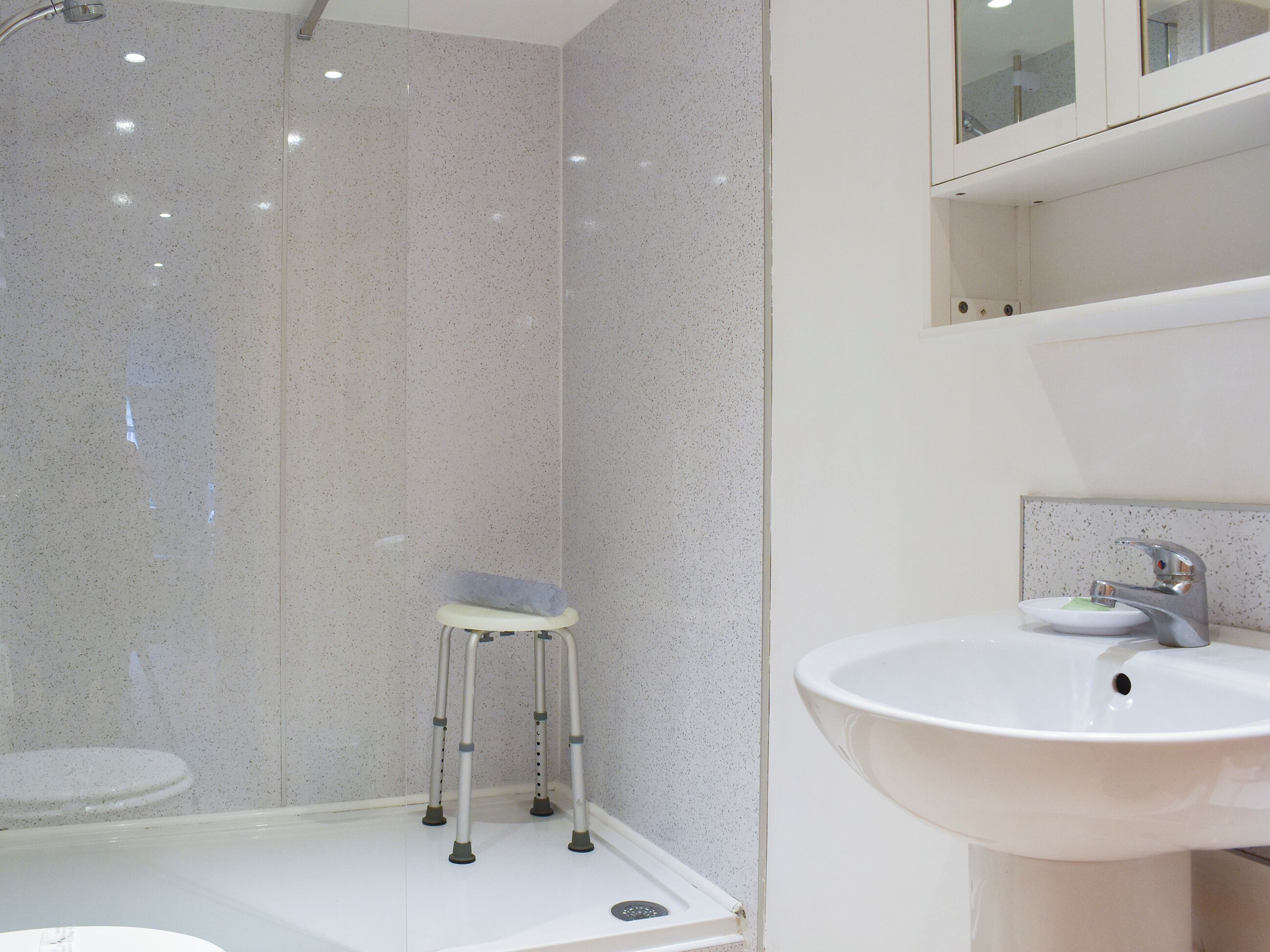Un bagno moderno con lavandino bianco, uno specchio e una zona doccia.