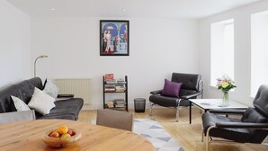 A modern living room with a wooden dining table, leather sofas, a black armchair, a bookshelf, and a framed picture on the wall. - 2 bedroom accommodation in Bonar Bridge (Bonar Bridge)