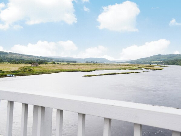 A river with a boat, surrounded by green fields and hills.