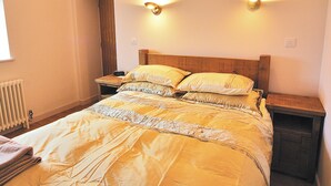 A bedroom with a bed, nightstands, a wooden headboard, and two wall-mounted lights.