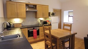 A compact kitchen with wooden cabinets, a microwave, a toaster, and a sink.