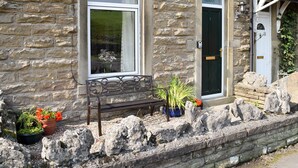 A stone building with a bench, potted plants, and a door labeled "Three Peaks House". - 3 bedroom accommodation in Horton in Ribblesdale, near Settle (Horton in Ribblesdale, near Settle)