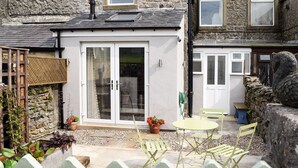 A stone house with a white door and a small patio area with a table and chairs. - 3 bedroom accommodation in Horton in Ribblesdale, near Settle (Horton in Ribblesdale, near Settle)