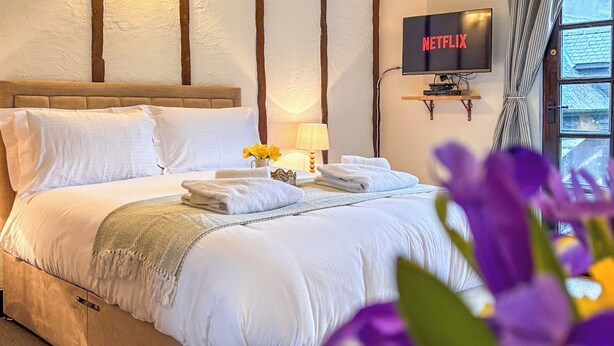 Une chambre d’hôtel avec un lit, une télévision, une lampe et une fenêtre avec des rideaux.