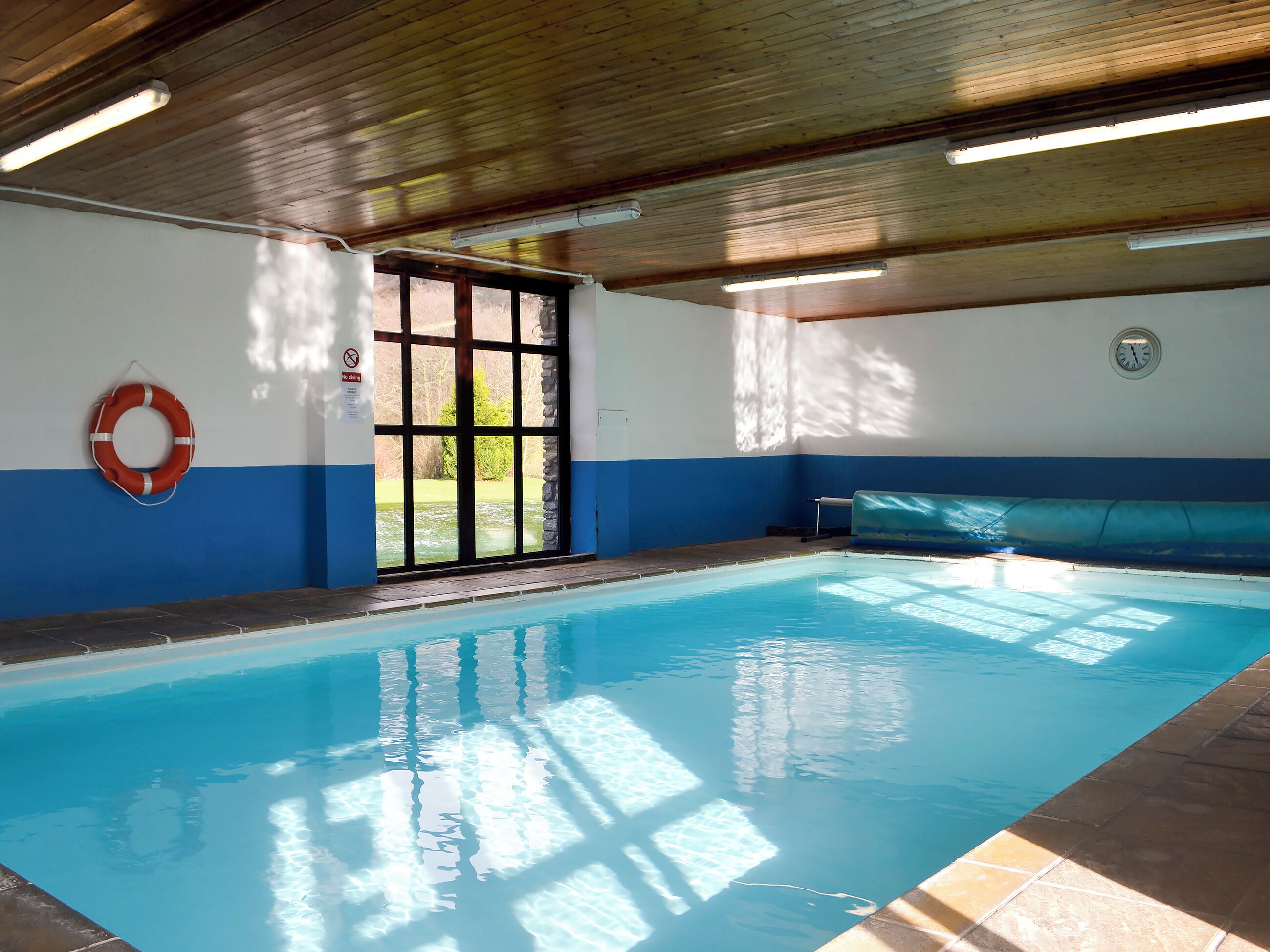 Ein Hallenbad mit Rettungsboje, einer Uhr und einer Bank.
