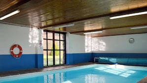 Une piscine intérieure équipée d’une bouée de sauvetage, d’une horloge et d’un banc.
