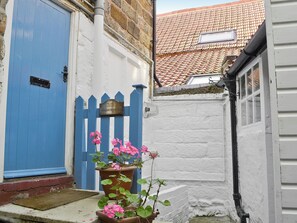 A blue door, a white wall, a blue picket fence, and a sign reading 'SHARROWHEAD'. - Sharrowhead Cottage - E4044 (Robin Hood’s Bay)